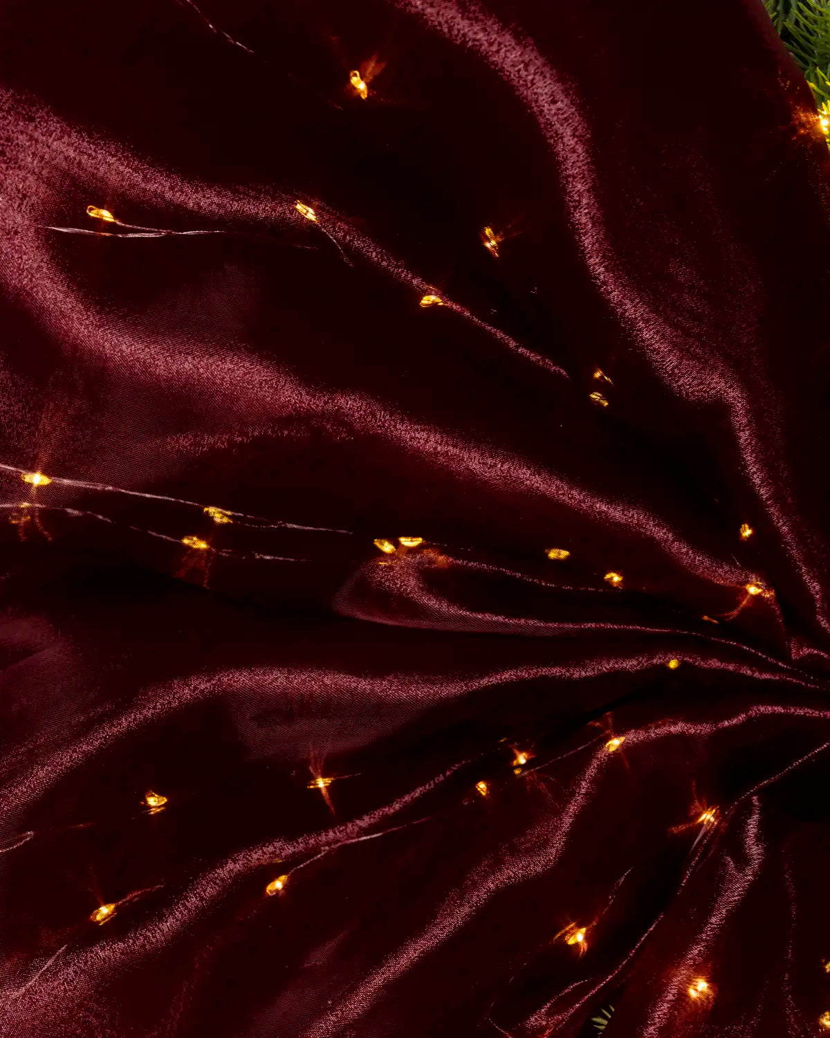 Close-up of burgundy bow fabric with warm white lights woven throughout