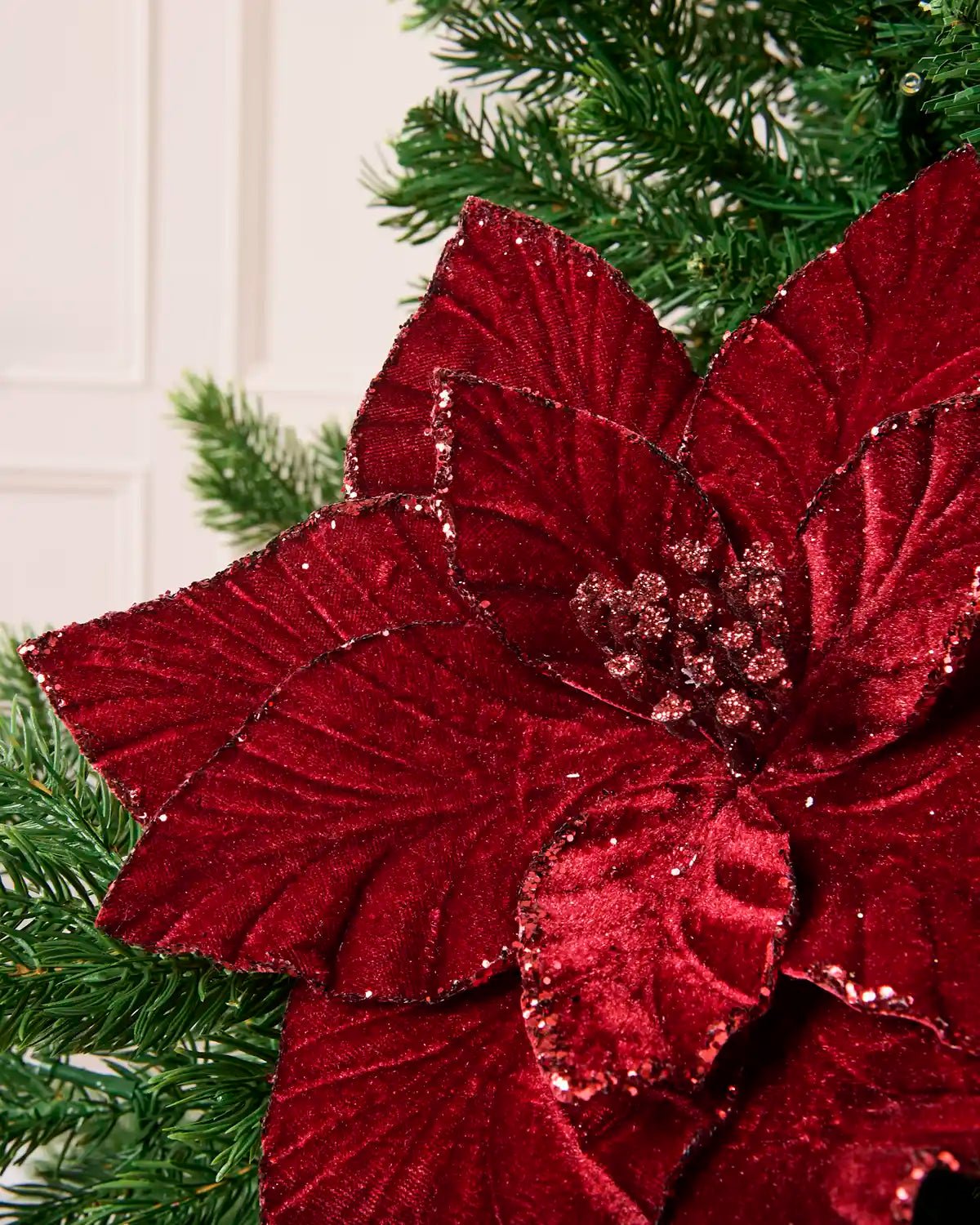 Close-up of burgundy velvet poinsettia petals with glittered edges and center detail
