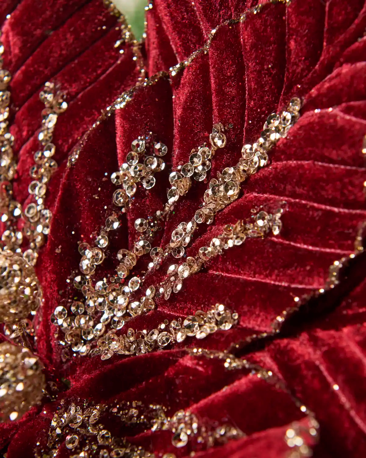 Close-up of burgundy velvet poinsettia petals with gold sequin detailing and glittered edges