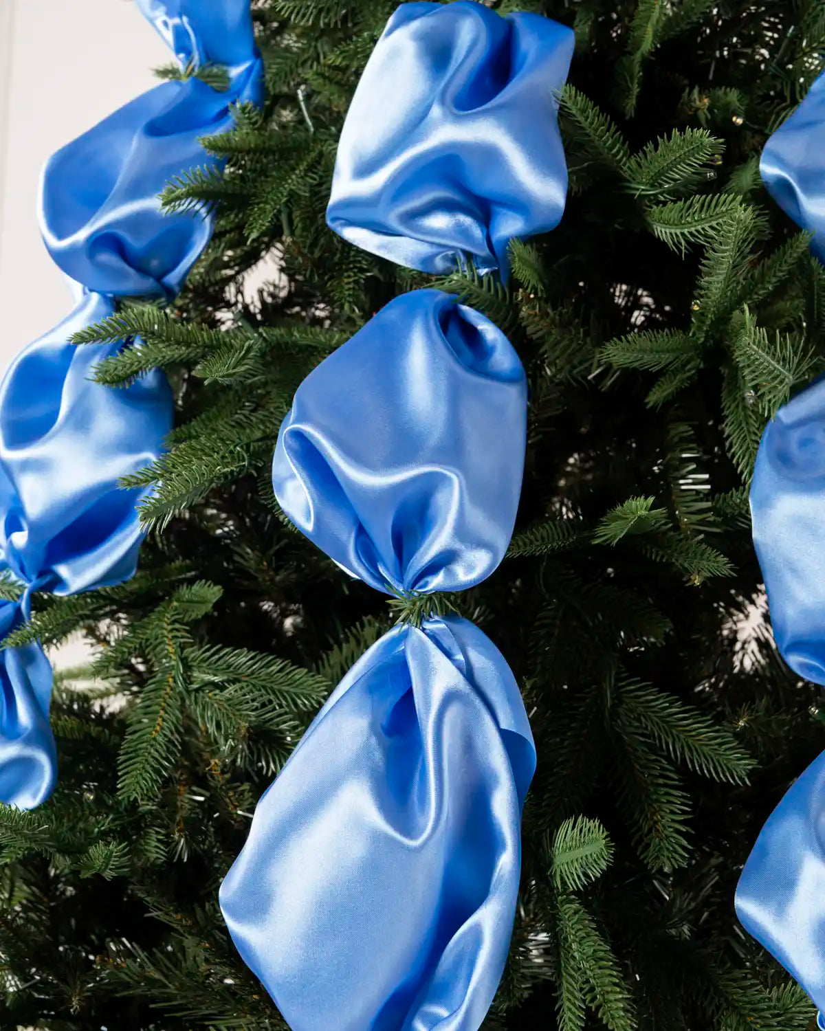Close-up of glossy ice blue satin ribbon fabric gathered into soft folds