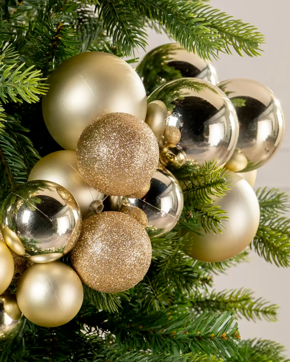 Close-up of gold baubles in a Gold Bauble Cluster Arch, featuring glitter, matte, and glossy finishes