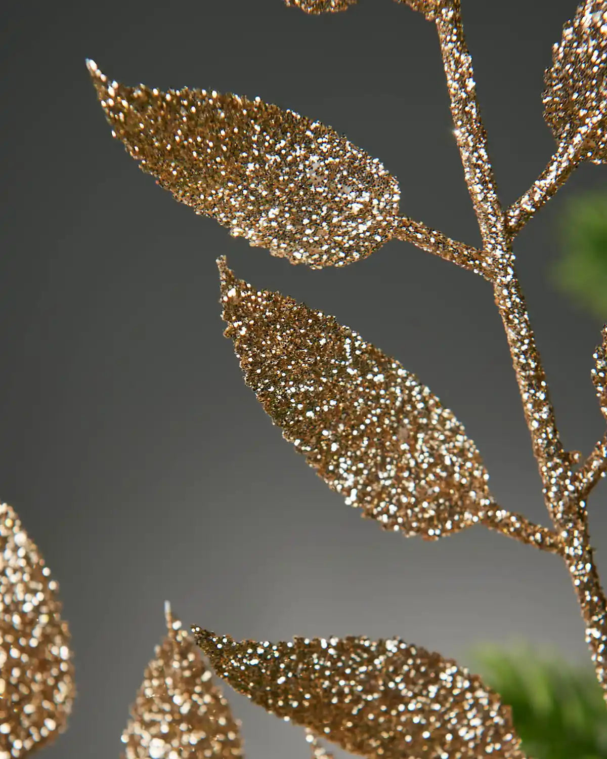 Close-up of a gold glittery branch with leaves on a dark background