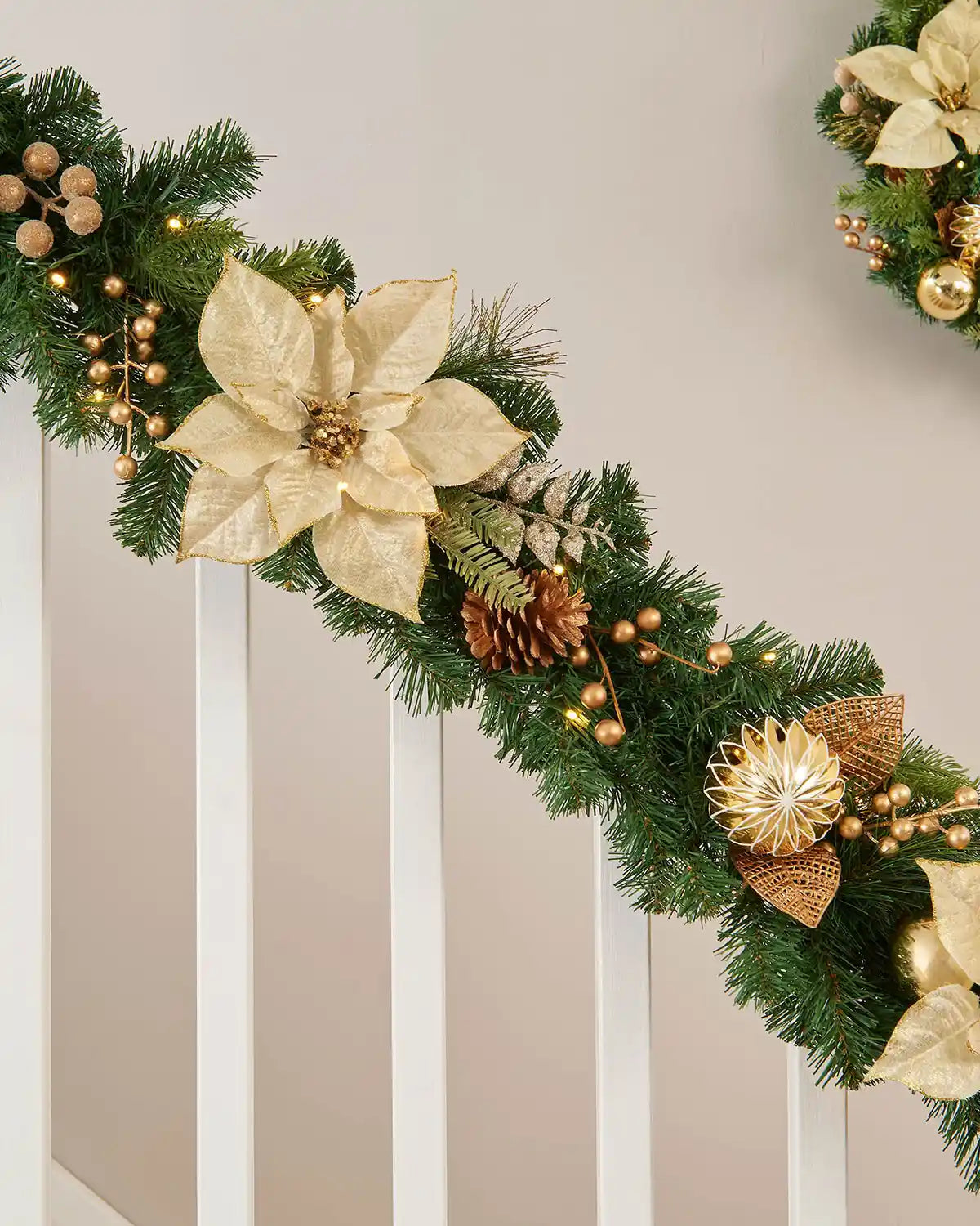 Close-up image of green garland on wooden staircase with pinecones and golden foliage