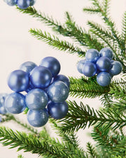 Close-up of ice blue glass berry cluster baubles with shiny and matt finishes on a Christmas tree.
