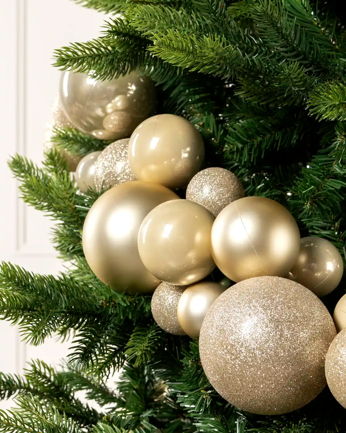 Close-up of latte bauble garland on a Christmas tree showing mixed sizes, matt, shiny and glitter finishes.