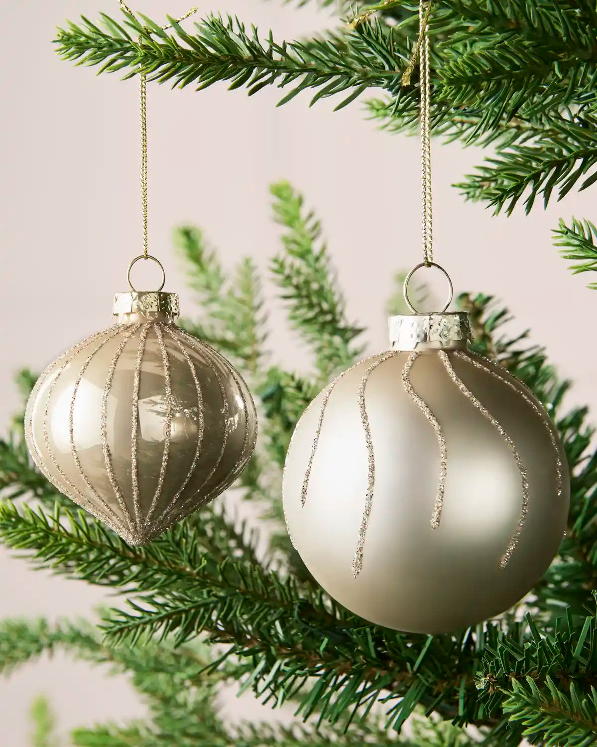 Close-up of latte onion-shaped and round glass baubles with glitter stripe patterns.
