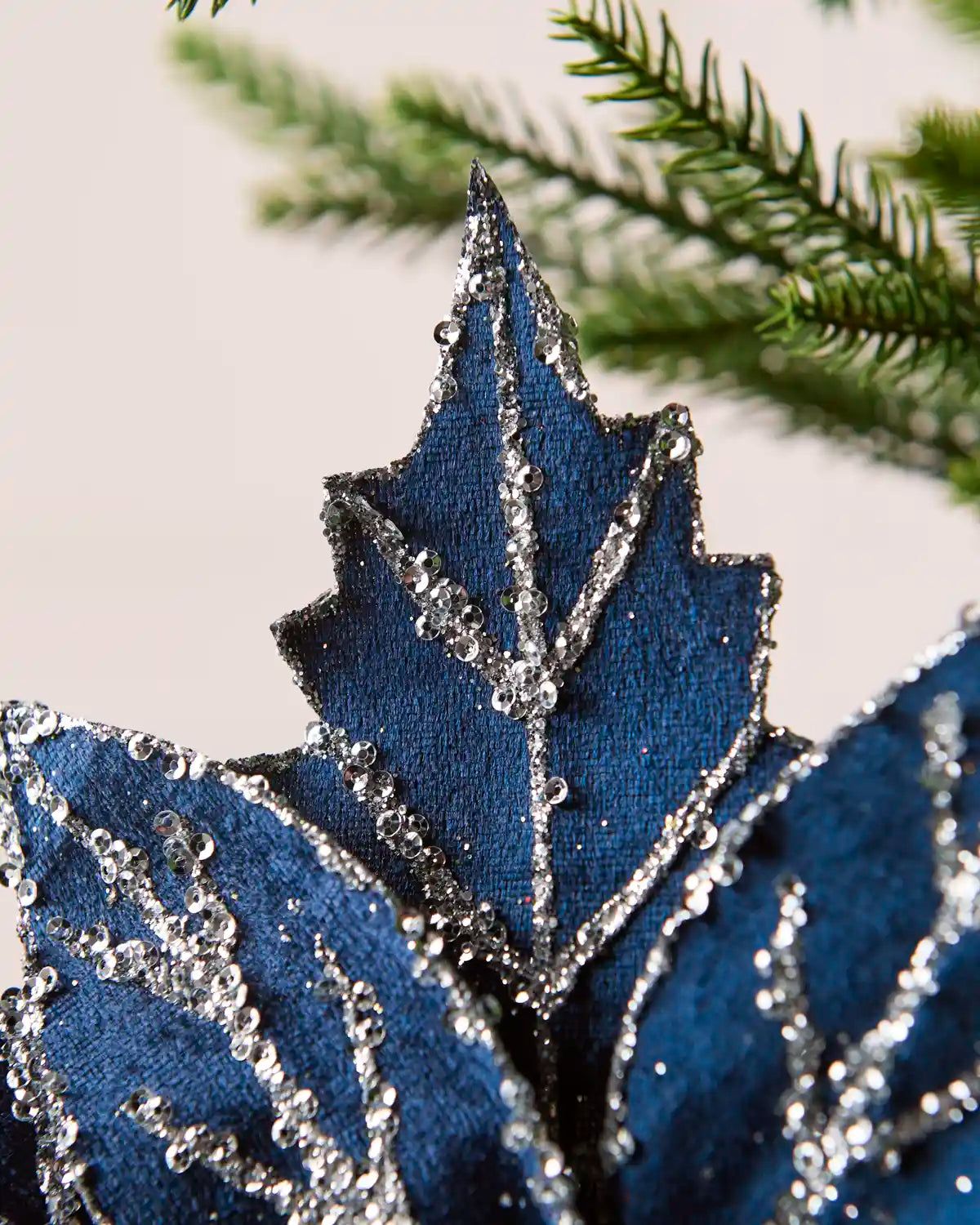 Close-up of navy blue poinsettia petals featuring silver glitter and sequined detailing