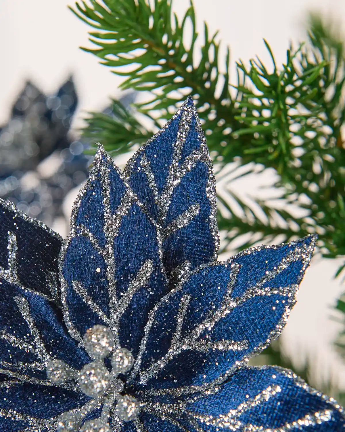 Close-up of navy blue poinsettia petals featuring silver glitter and sequined detailing