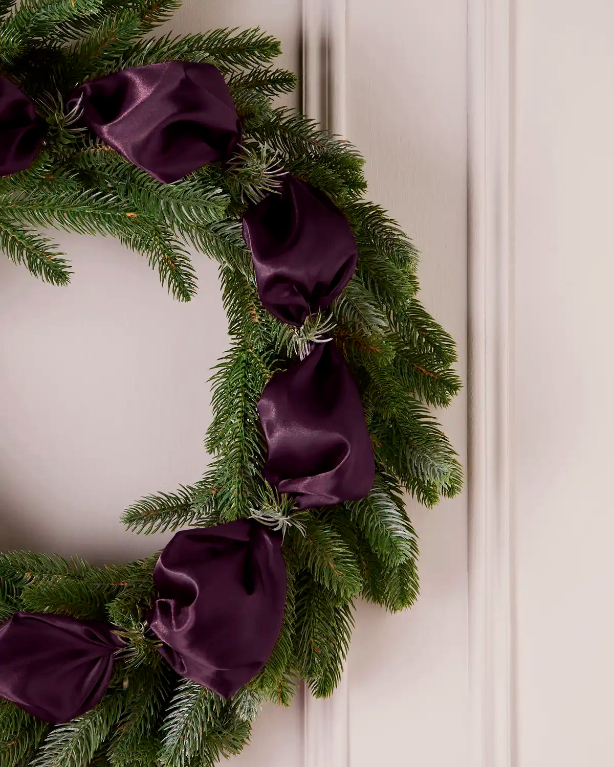 Close-up of purple satin ribbon wrapped around the branches of a Christmas Wreath