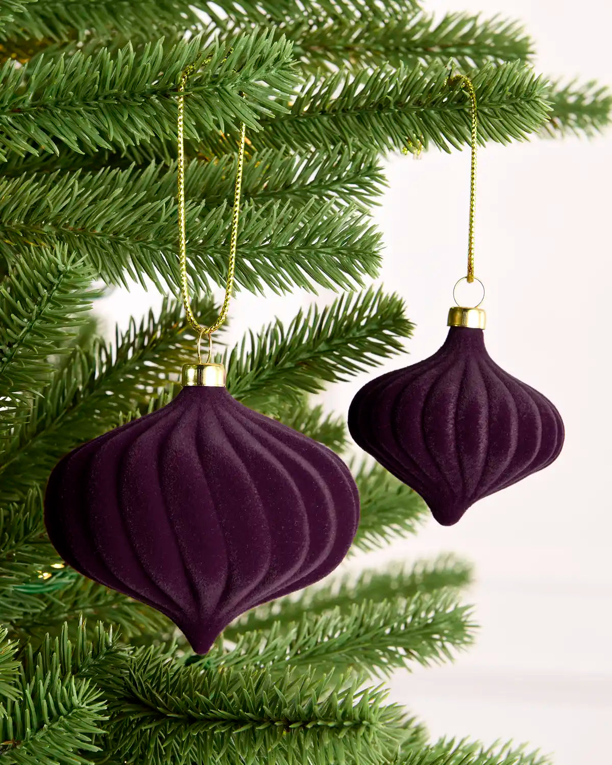 Close-up of purple velvet baubles on a Christmas tree, showcasing their soft, plush texture and gold caps