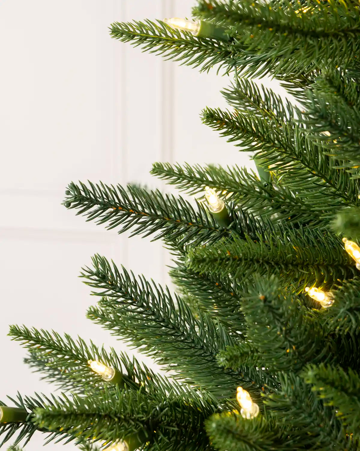 Close-up of realistic green spruce branches with warm white lights
