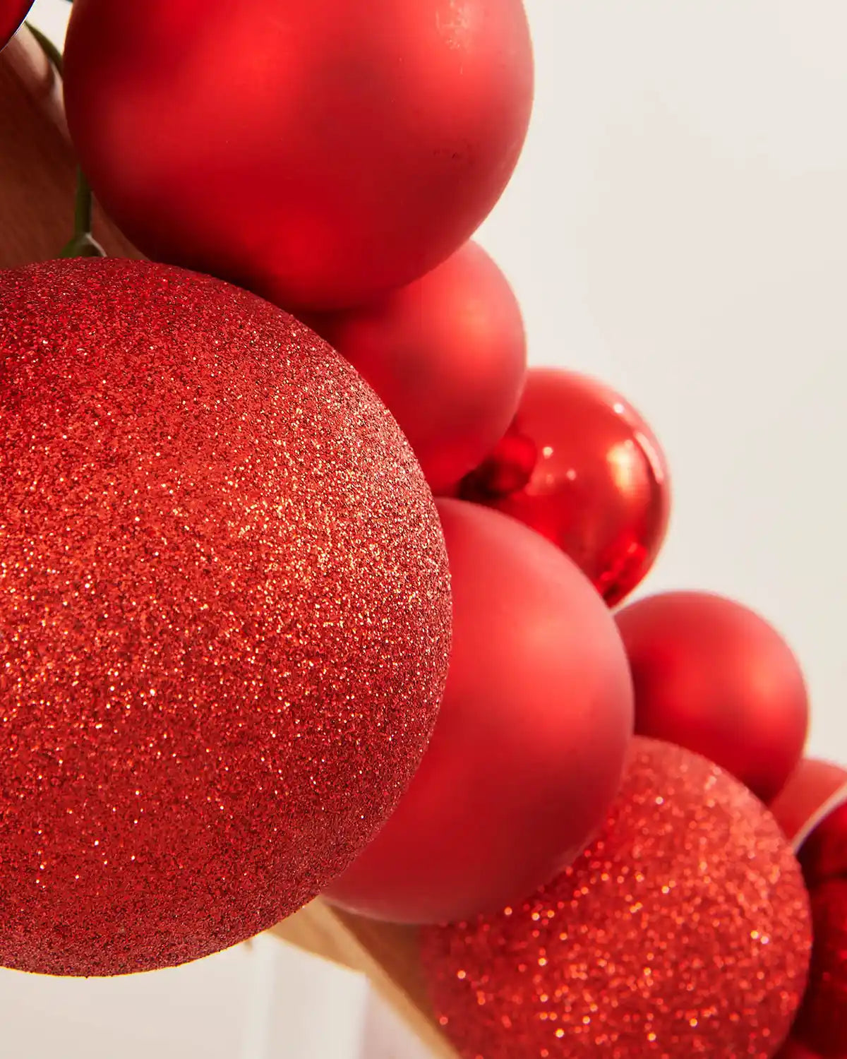 Close-up of red Christmas bauble garland with glitter on a white background