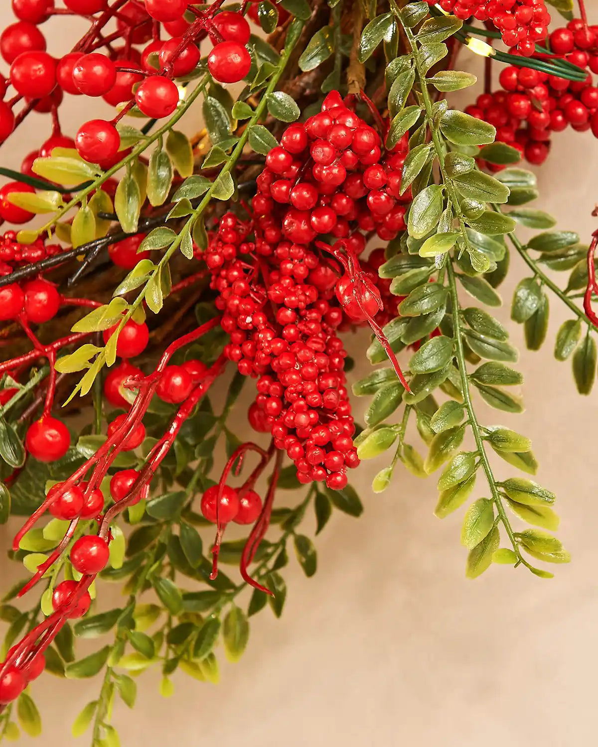 Close-up of red berries and green leaves on a beige background