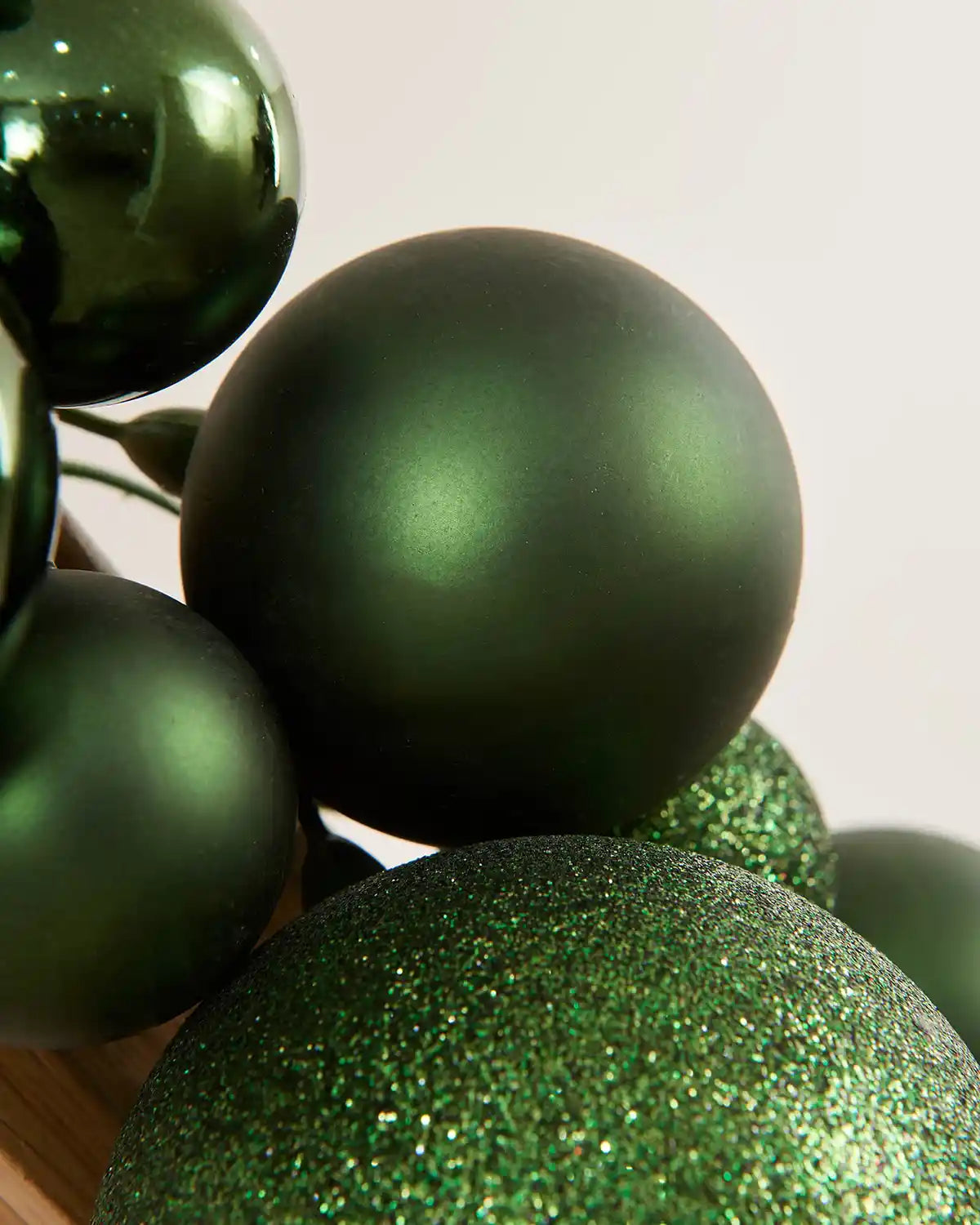 Close-up of sage green glitter and shiny baubles on a light background
