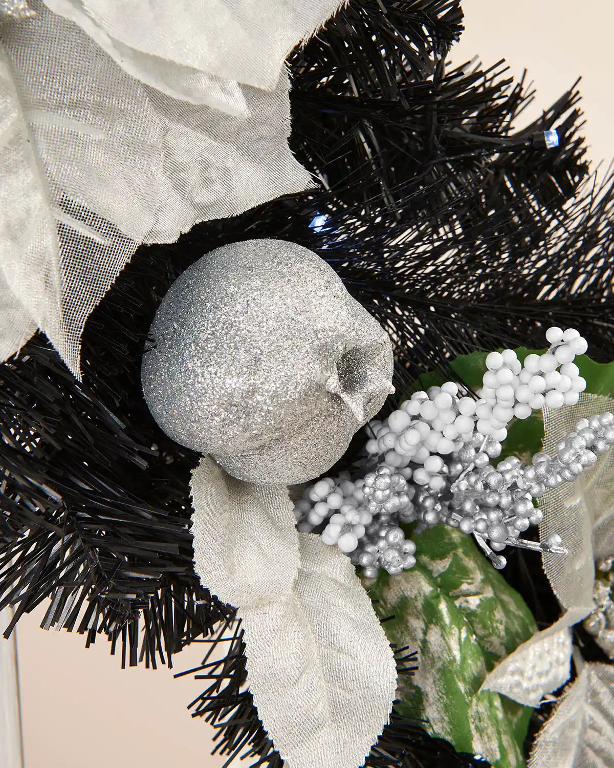 Close-up of the silver fruit and berries on a black garland with bright white lighting