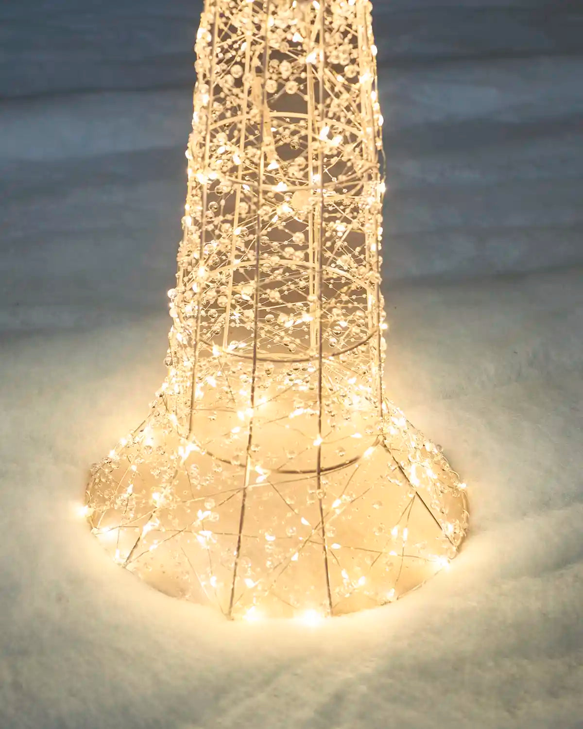 Close-up of the illuminated base of the Pre-Lit Twinkling Beaded Lamp Post standing in snow with warm white lights