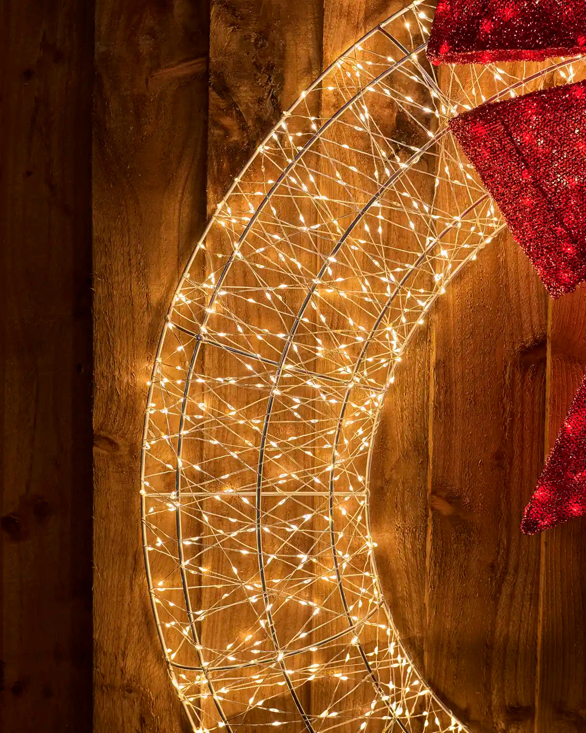 Close-up of the illuminated metal wreath frame showing arrangement of warm white lights and the edge of the red bow