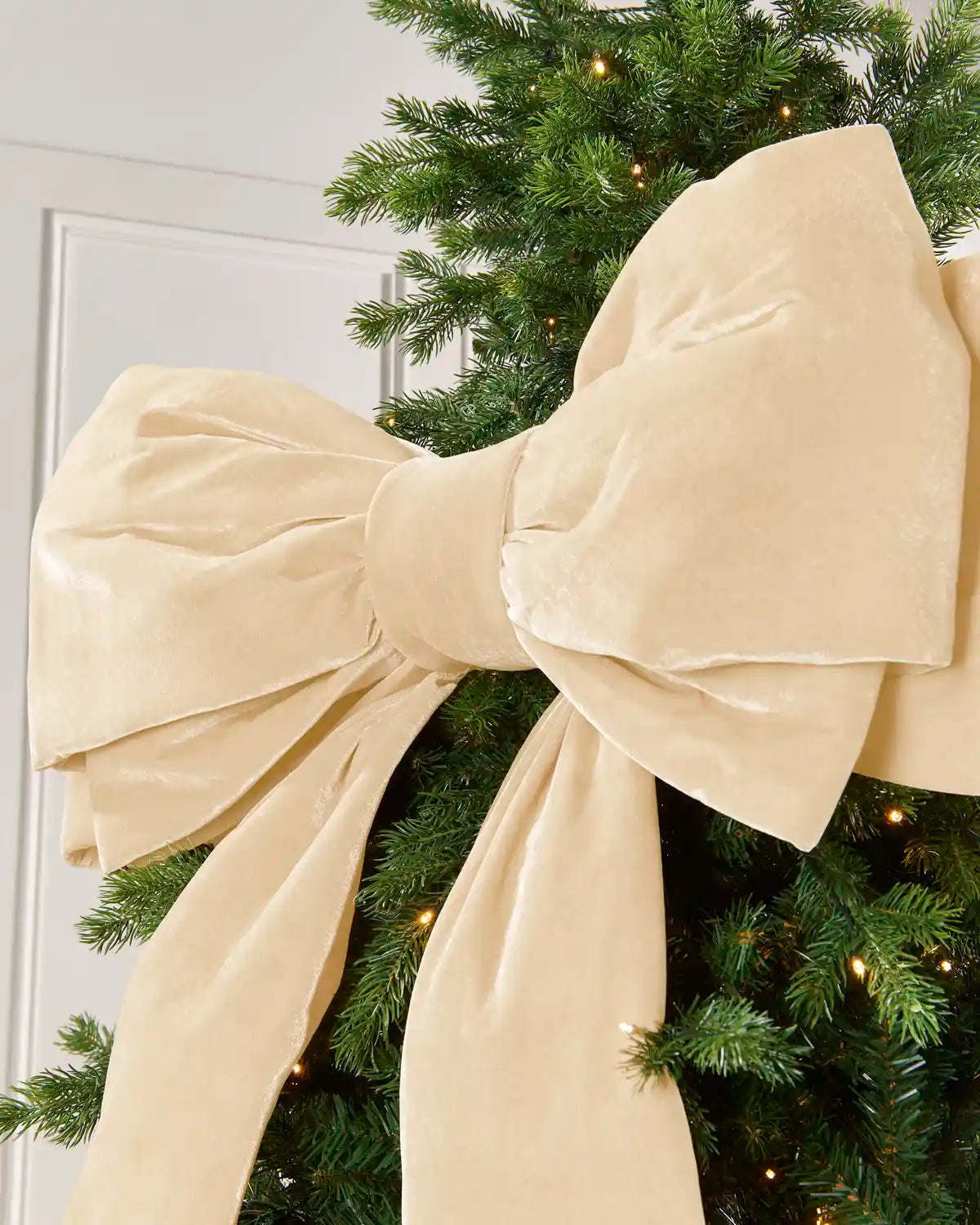 Close-up of the large latte velvet Christmas bow showing its layered structured loops and soft finish.
