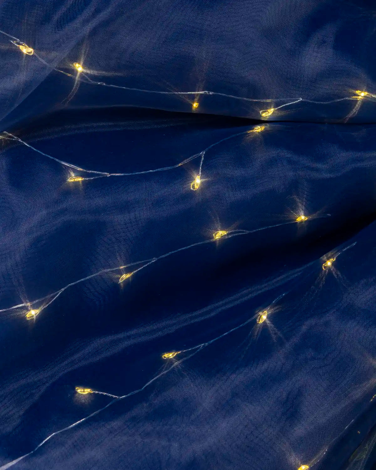 Close-up of the navy blue fabric showing its rich texture and warm white lights.