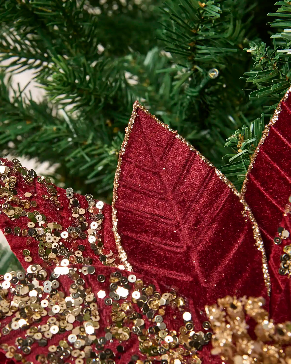Close-up of the pointed Burgundy & Gold poinsettia petals showing the textured fabric and gold glitter outlining the edges and vein patterns.