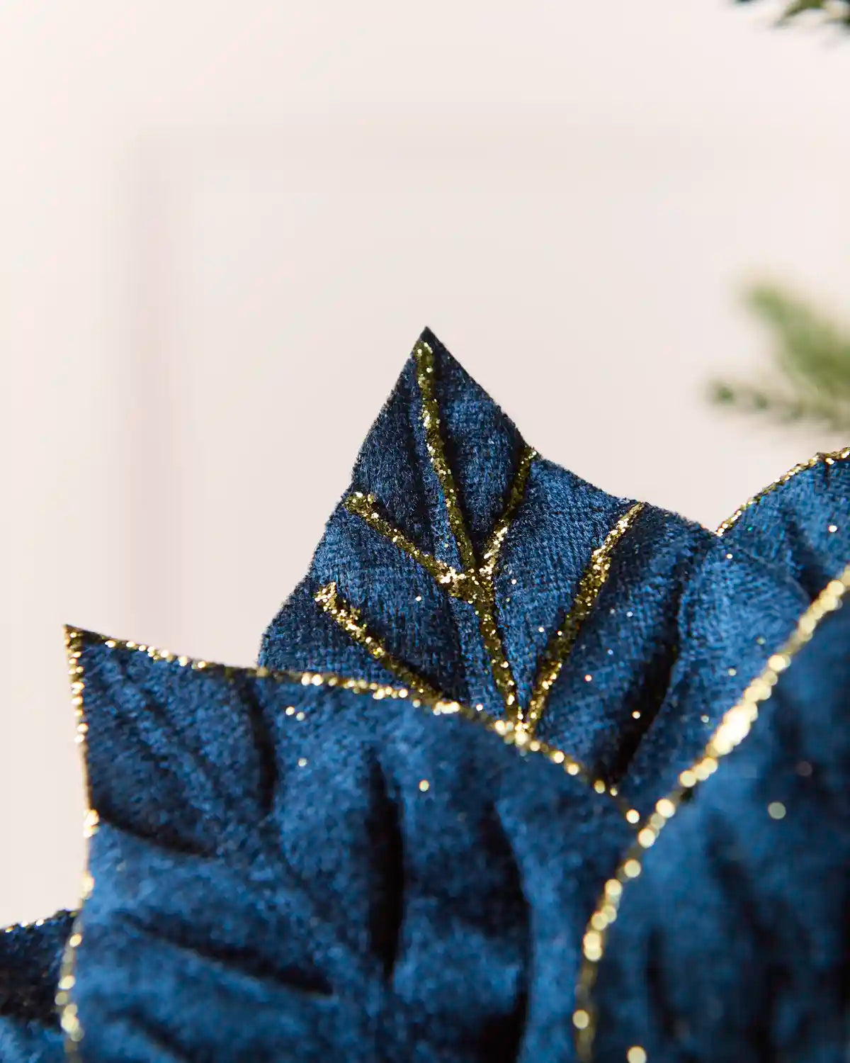 Close-up of the pointed Navy poinsettia petals showing the textured fabric and gold glitter outlining the edges and vein patterns.