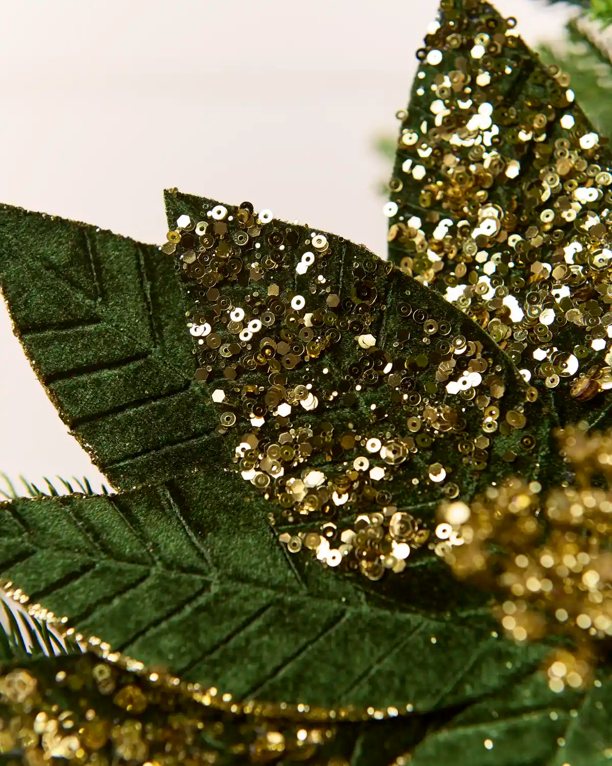 Close-up of the pointed Sage Green & Gold poinsettia petals showing the textured fabric and gold glitter outlining the edges and vein patterns.