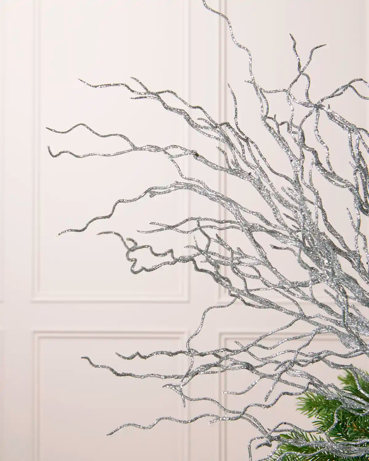 Close-up of the silver glittered branches of a Glitter Twig Tree Topper, showing the twisted stems 