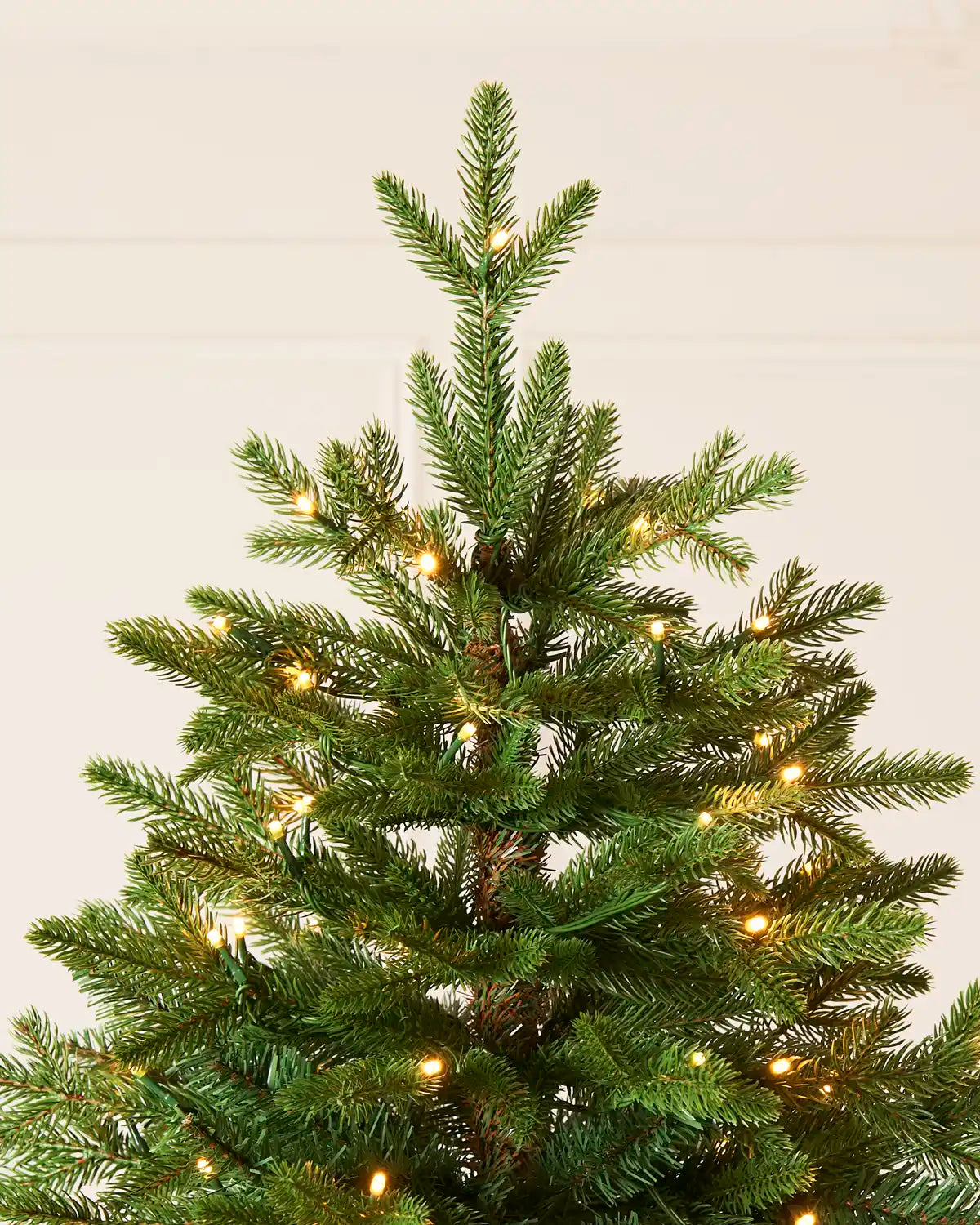 Close-up of the top branches of Pre-Lit Woodland Pine Christmas Tree, 6.5ft, with warm white lights