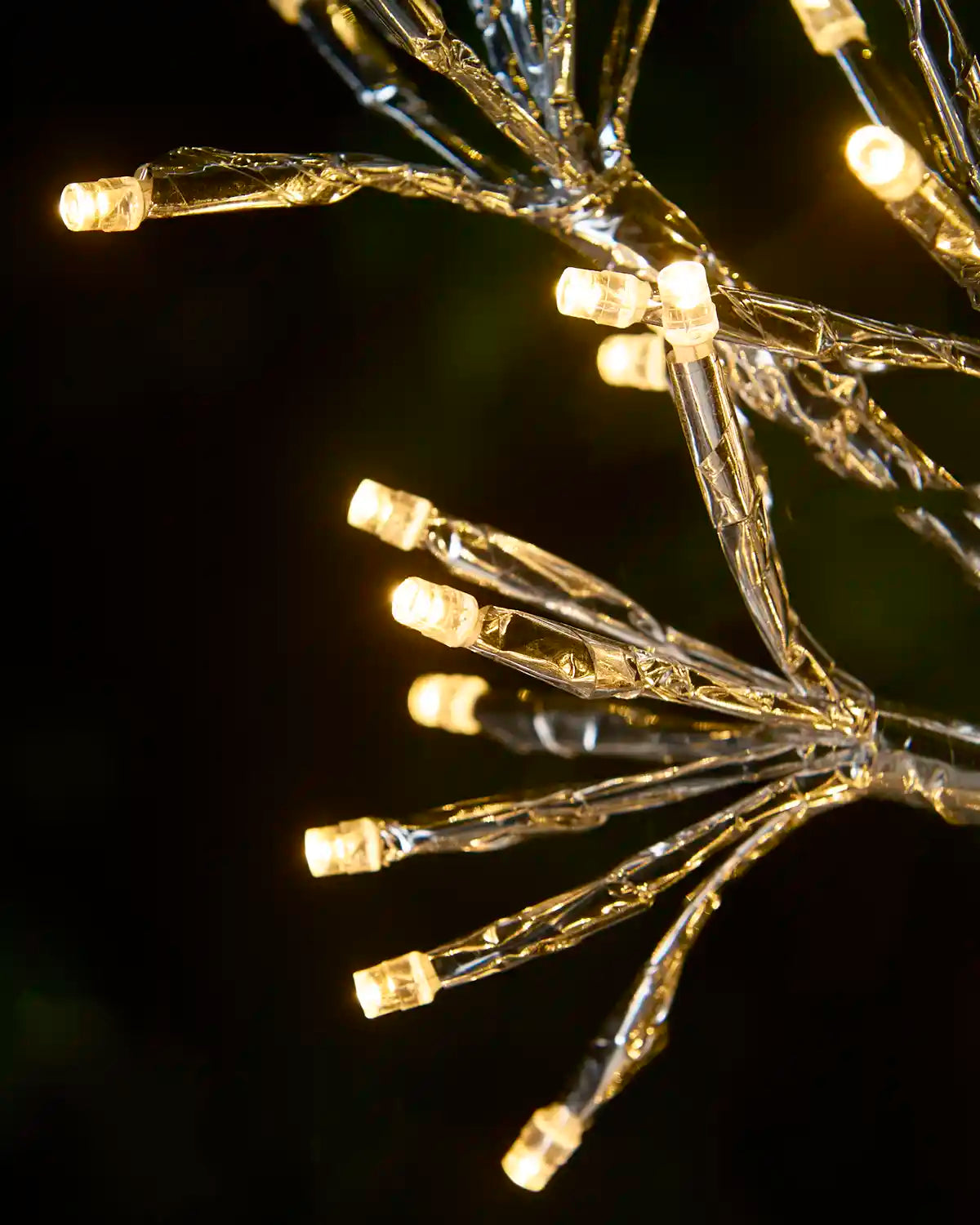 Close-up of warm white LED branch lights on a dark background.