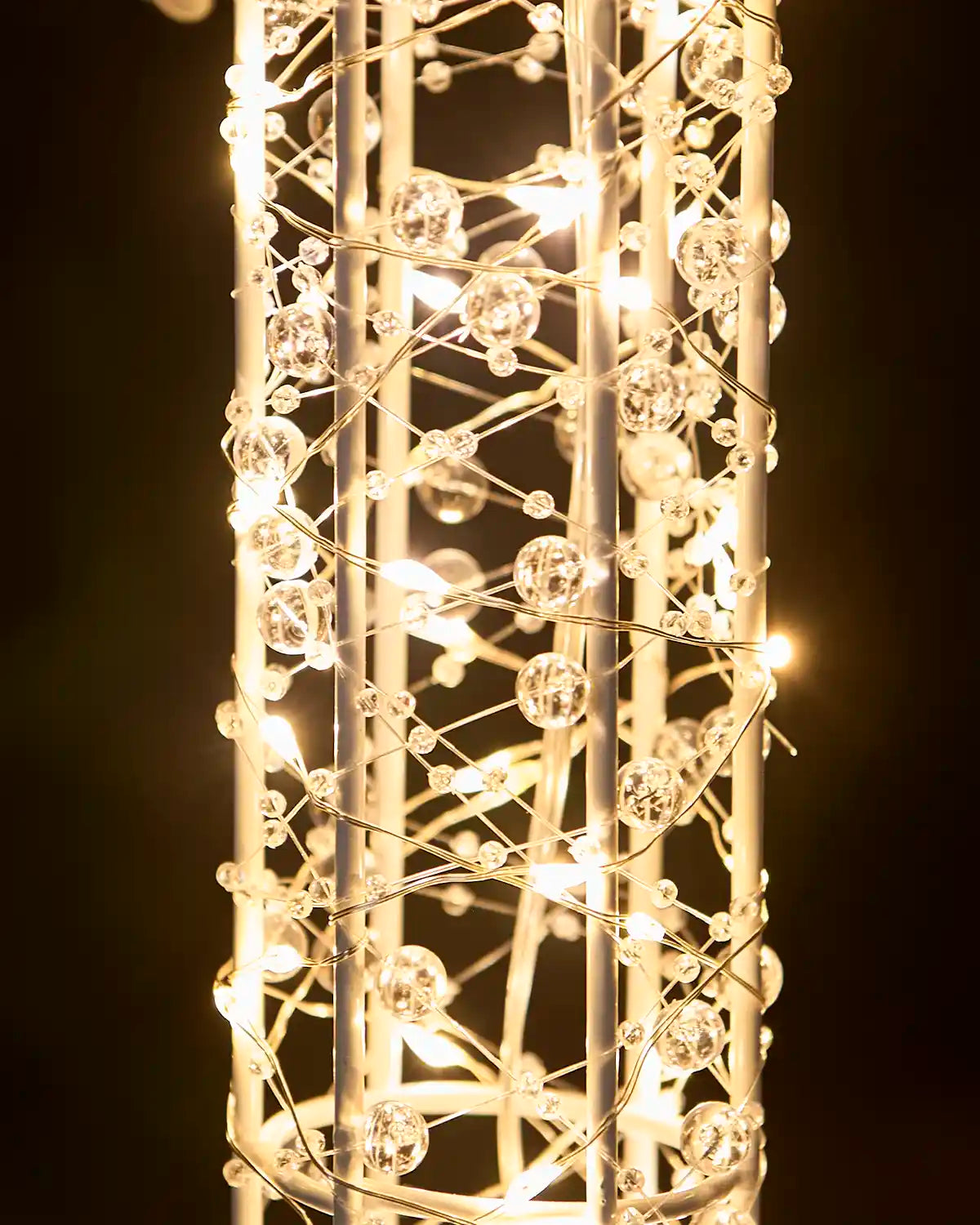Close-up of warm white lights and clear beads wrapped around the wire frame