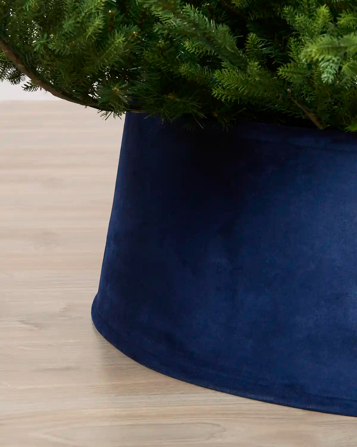 Close-up view of the Navy velvet tree skirt, highlighting its rich texture and curved edge around the Christmas tree base
