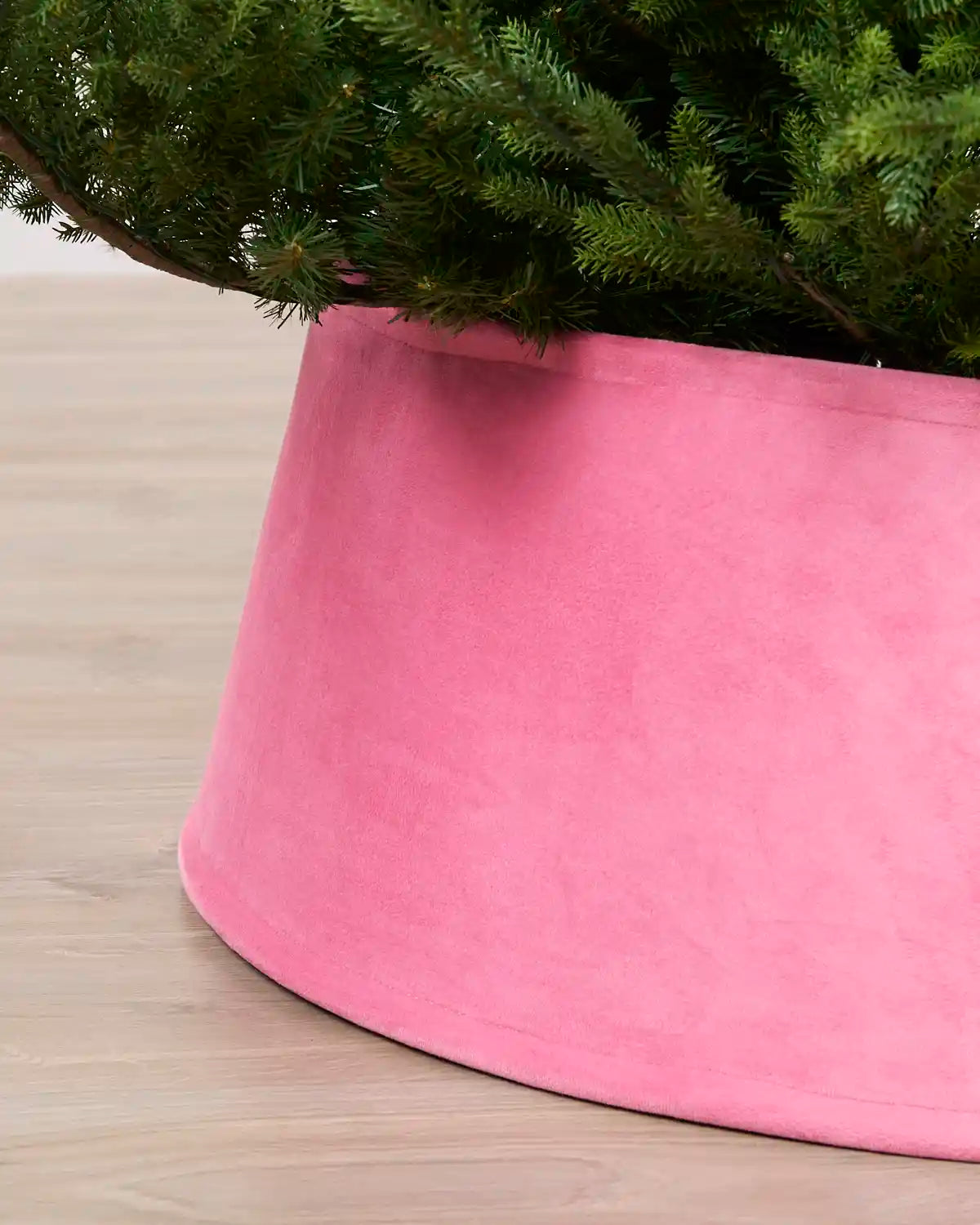 Close-up view of the Pink velvet tree skirt, highlighting its rich texture and curved edge around the Christmas tree base
