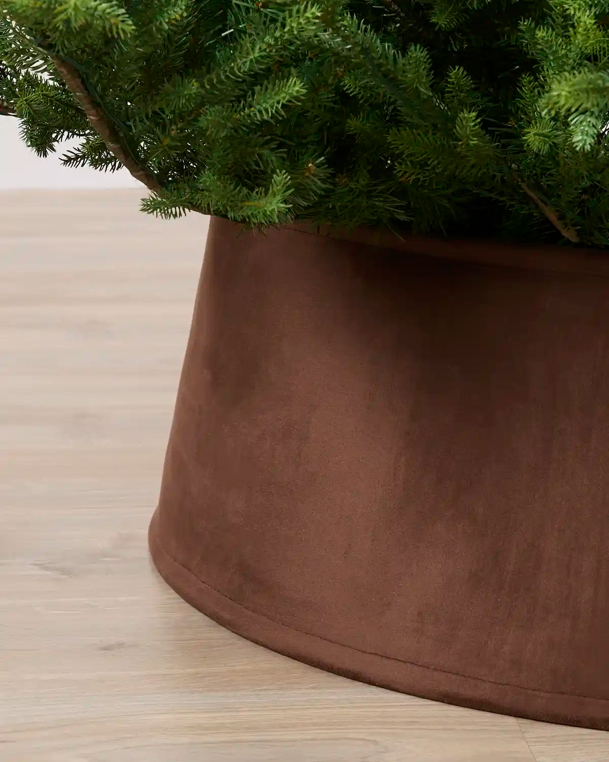 Close-up view of the espresso velvet tree skirt, highlighting its rich texture and curved edge around the Christmas tree base
