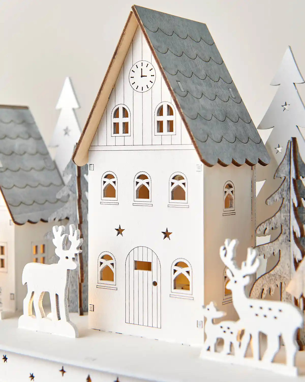 Close-up of 40cm pre-lit white wooden village featuring house with warm white light and reindeer standees