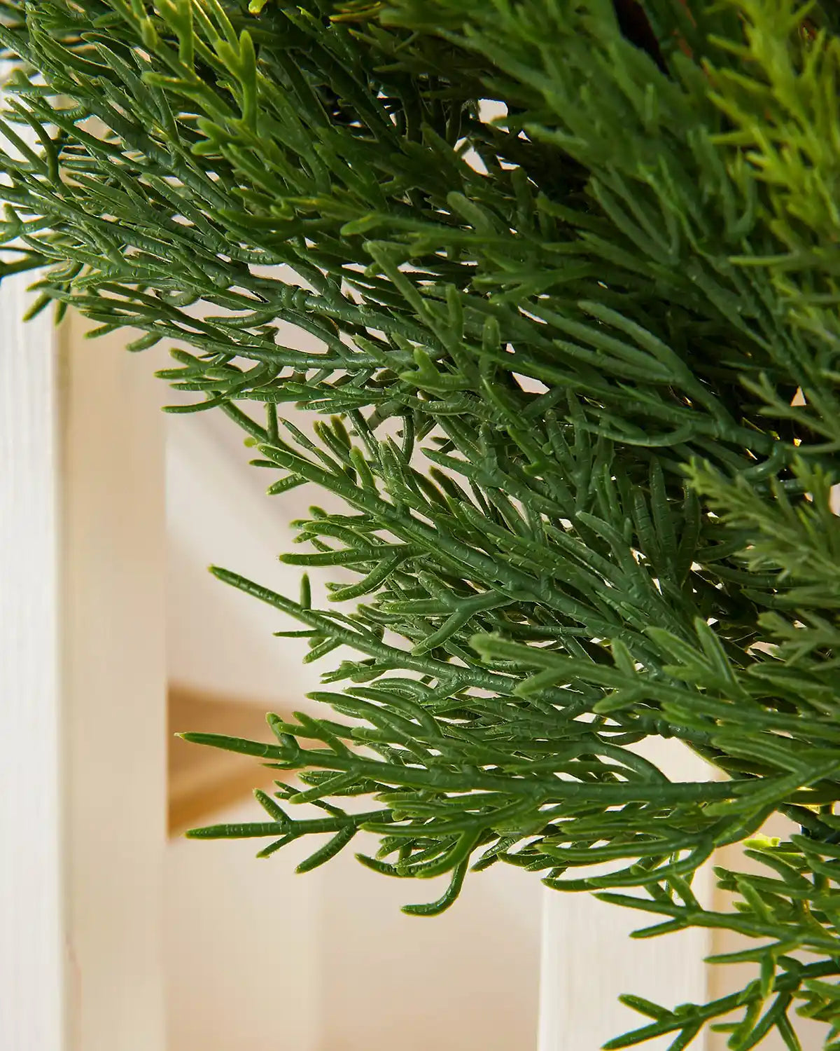 Close-up of 9ft pre-lit cypress fir garland branches on white wooden staircase showcasing pine needle detail
