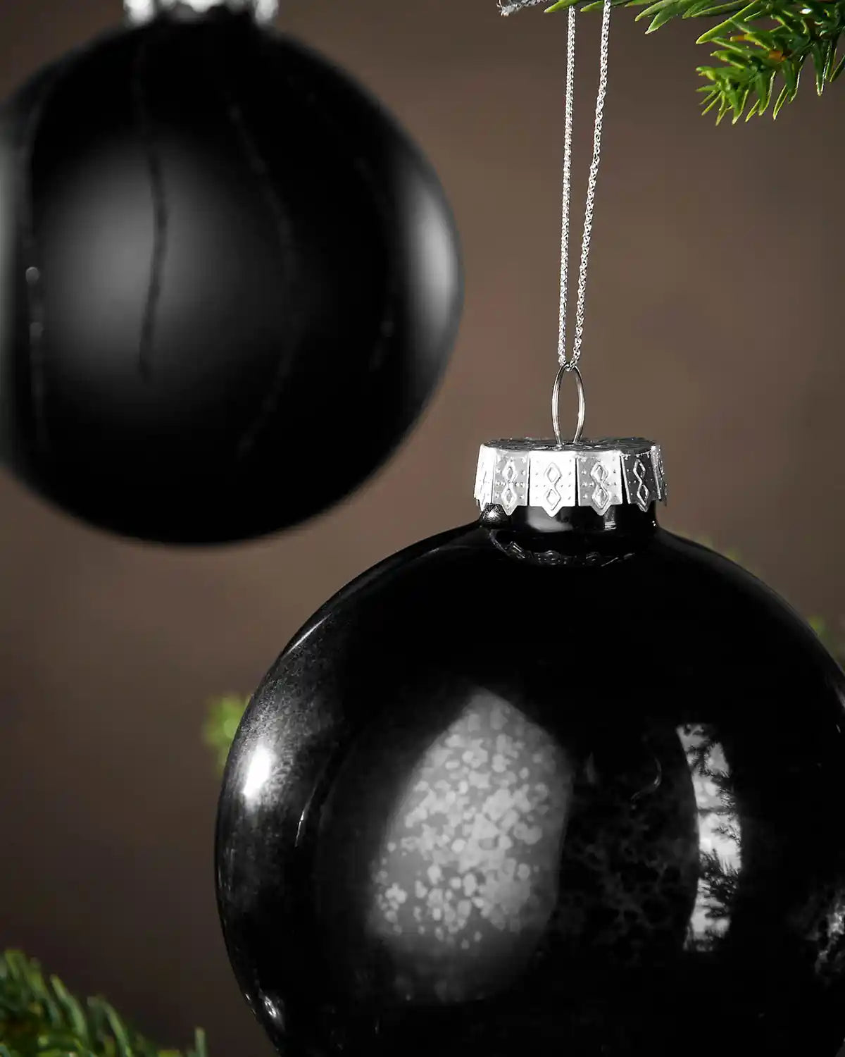 Close up Black Christmas baubles hanging on a tree with a brown background