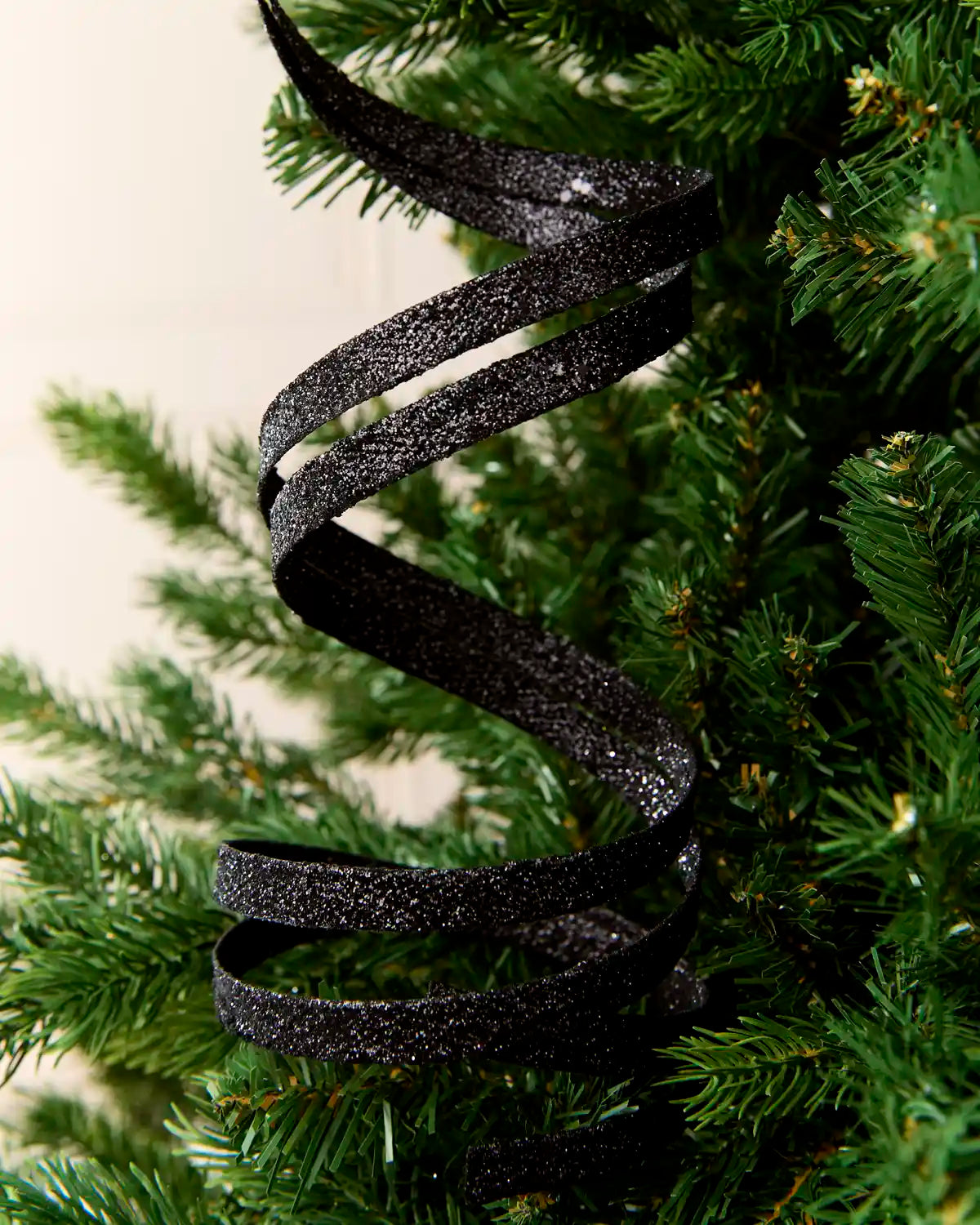 Close up Black Glitter Spiral Swirl Pick hanging from Christmas tree
