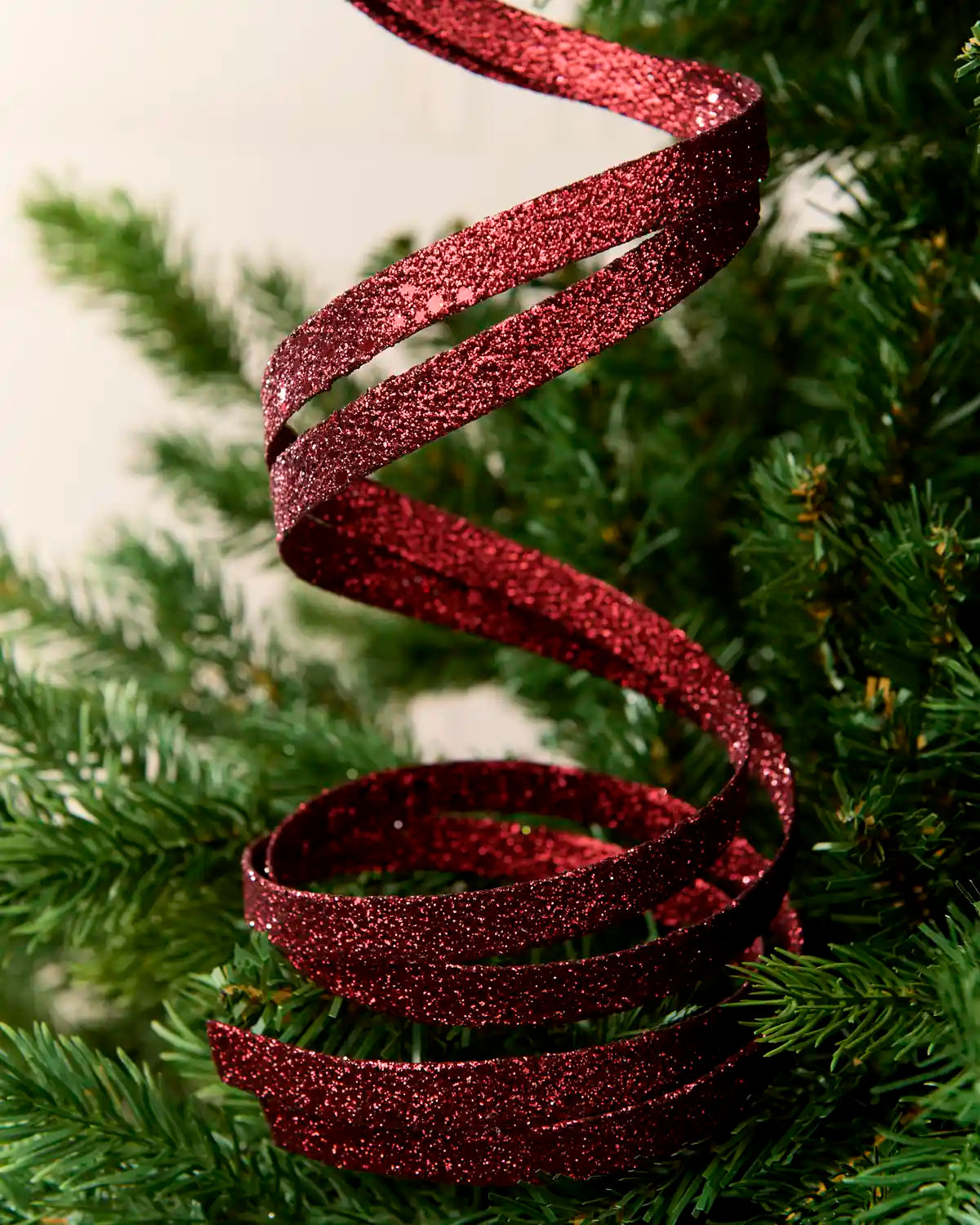 Close up Burgundy Glitter Spiral Swirl Pick hanging from Christmas tree
