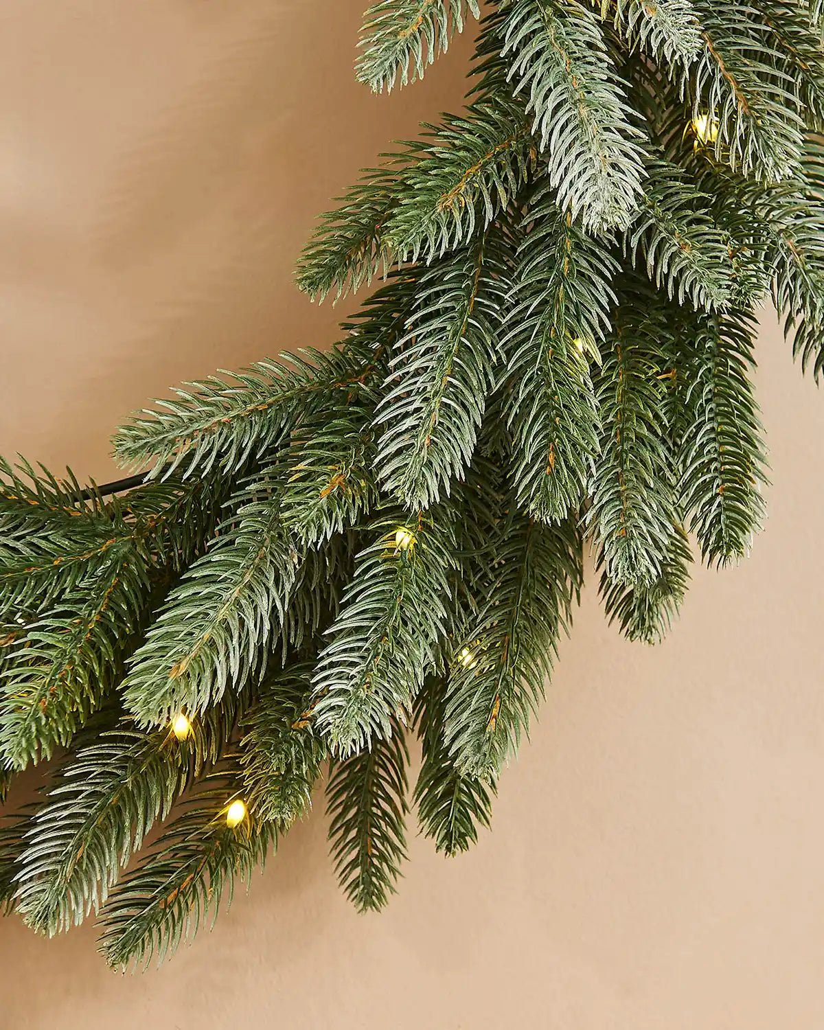 Close up Christmas wreath with lights on a beige background
