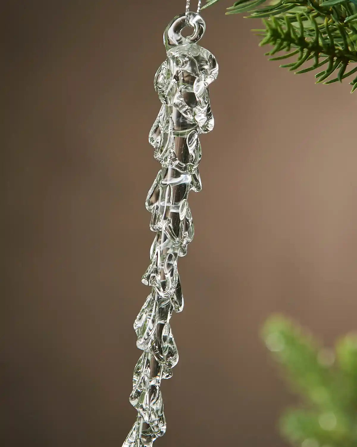 Close up Crystal icicle ornament hanging on a branch with a brown background
