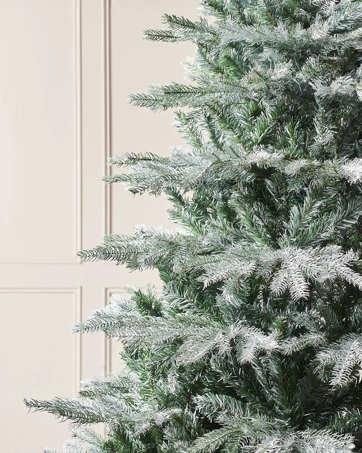 Close up Frosted artificial Christmas tree against a neutral wall
