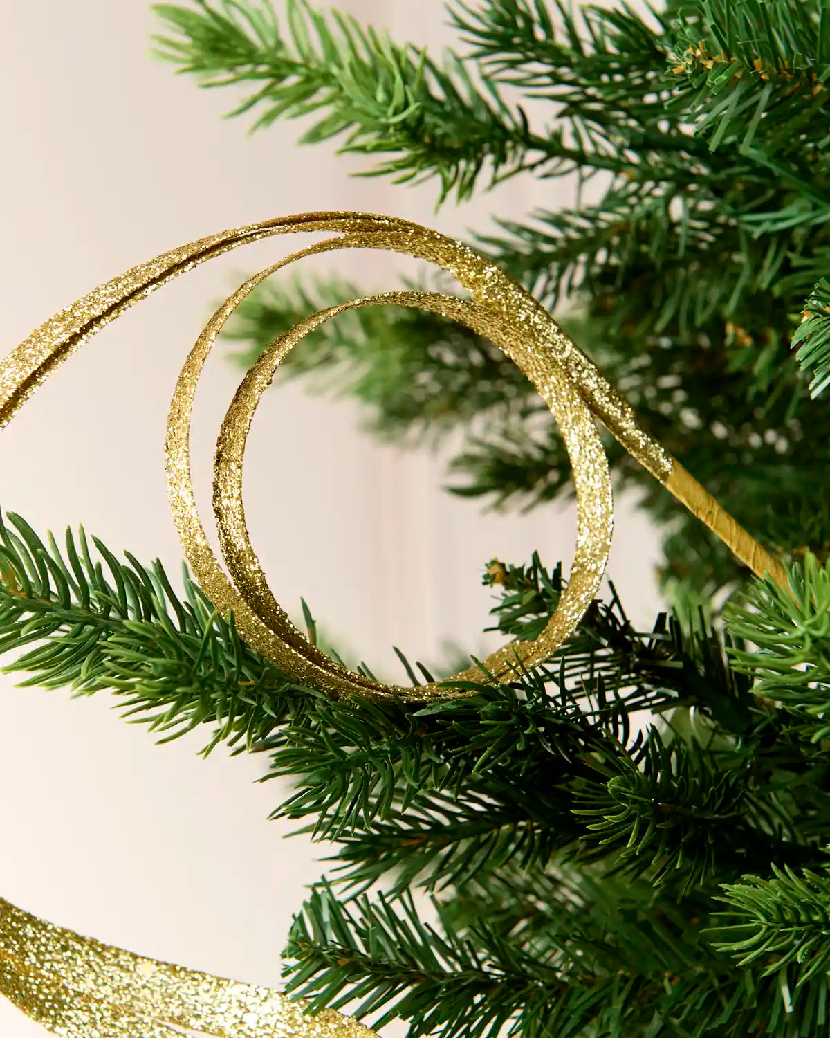 Close up Gold Glitter Spiral Swirl Pick hanging from Christmas tree
