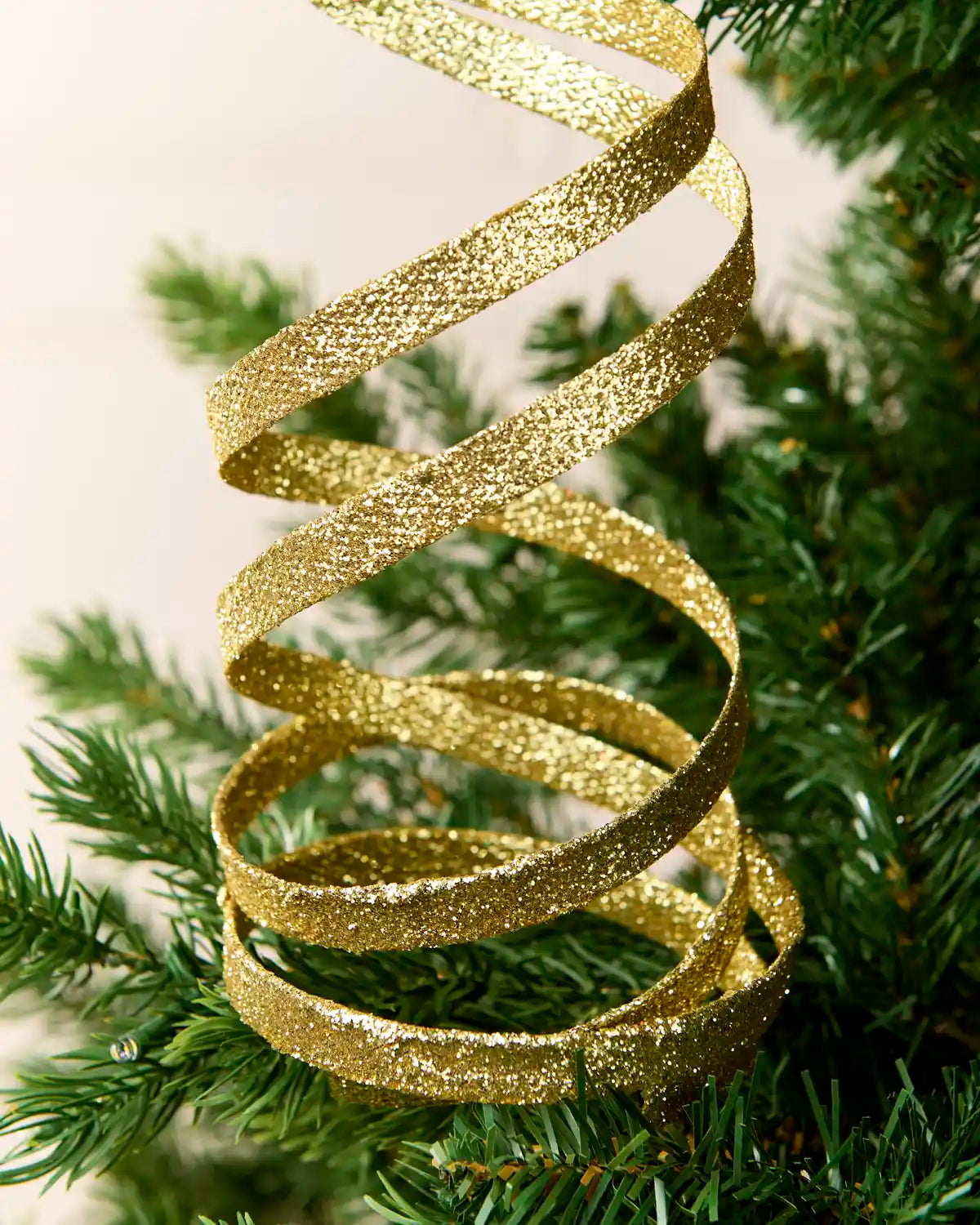 Close up Gold Glitter Spiral Swirl Pick showing Gold glitter details with green and cream blurred background