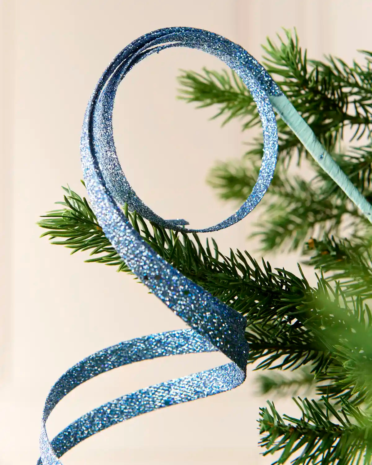 Close up Ice Blue Glitter Spiral Swirl Pick with green and cream blurred background

