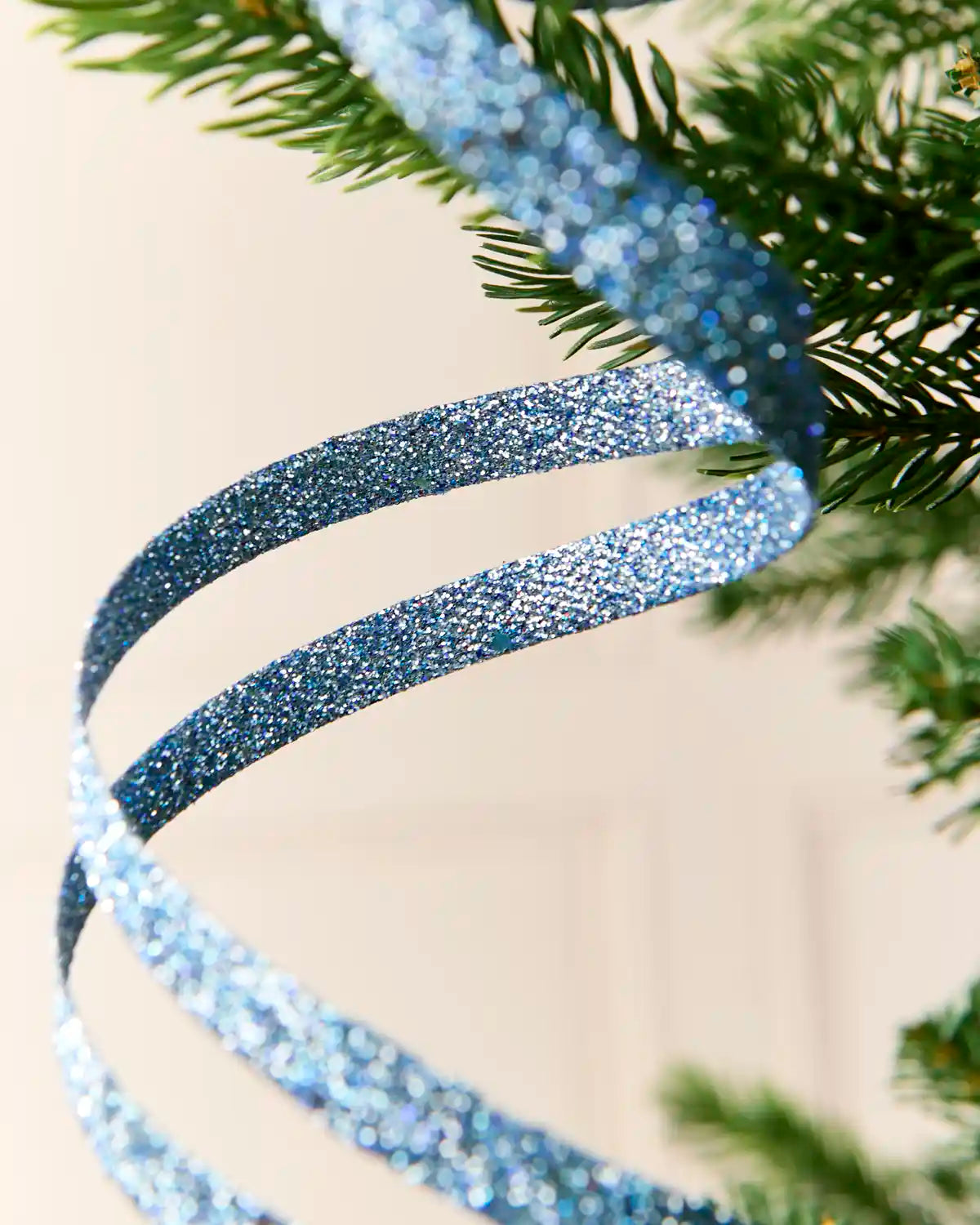 Close up Ice Blue Glitter Spiral Swirl Pick showing ice blue glitter details with green and cream blurred background