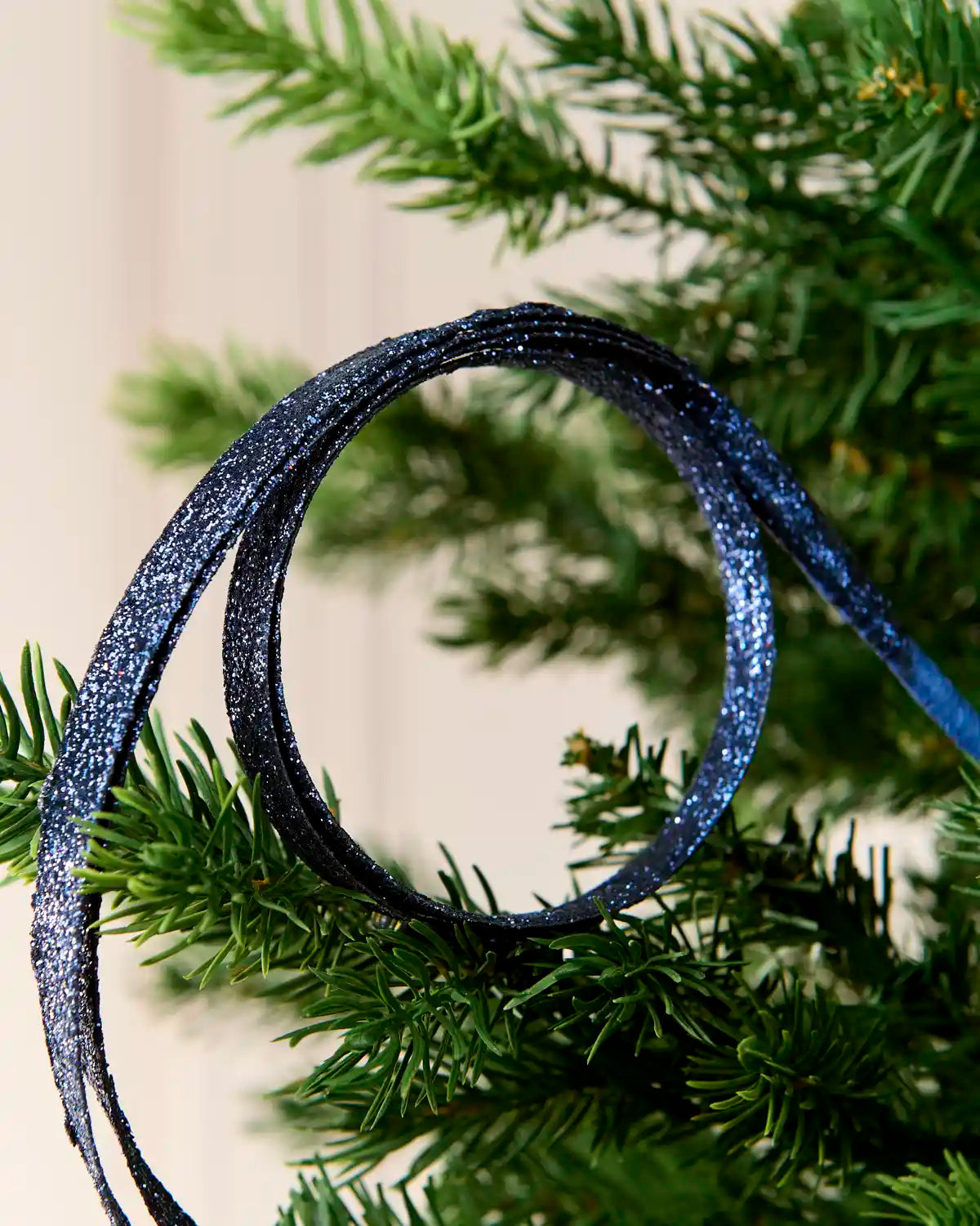 Close up Navy Glitter Spiral Swirl Pick hanging from Christmas tree
