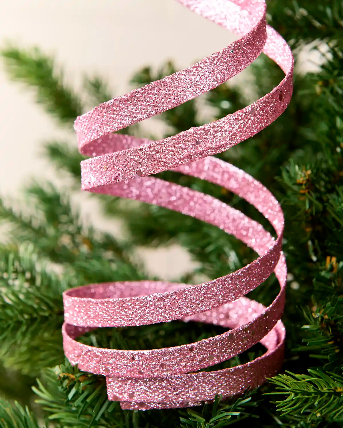 Close up Pink Glitter Spiral Swirl Pick hanging from Christmas tree
