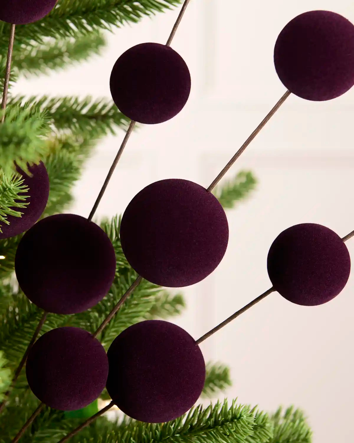 Close up Purple bauble pick on a Christmas tree against a cream background