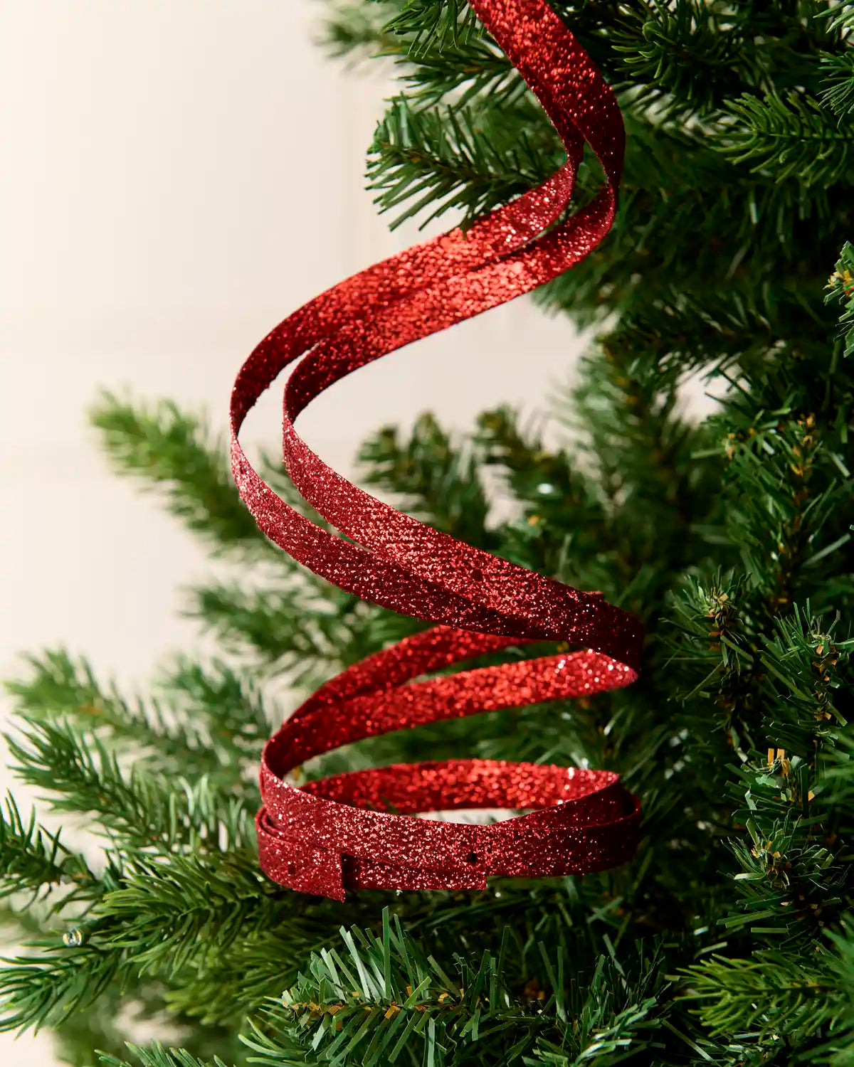 Close up Red Glitter Spiral Swirl Pick hanging from Christmas tree