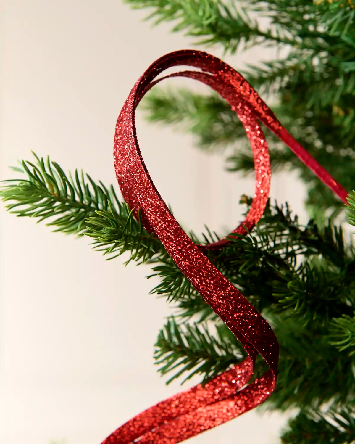 Close up Red Glitter Spiral Swirl Pick showing red glitter details with green and cream blurred background